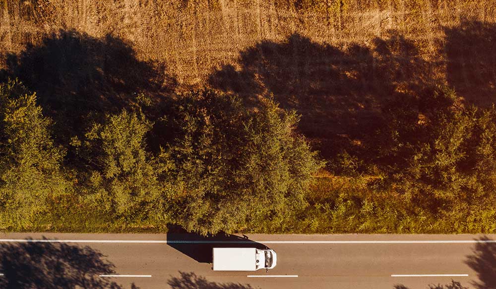 View of truck dribing along a road with trees on the side of the road